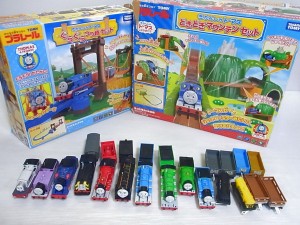 TOMY プラレールの、きかんしゃトーマス　どきどきマウンテンセットと、ぐらぐら吊り橋セットの外箱が有り、その前にはきかんしゃトーマスのプラレールの車両が並べられている。