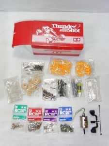 タミヤ Thunder Shot RCの赤い箱の中身。ネジやモーター。黄色のパーツなどが見えている。