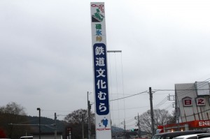 碓氷峠鉄道文化むらの看板の画像。曇空。鉄道のイラストなども描かれている。